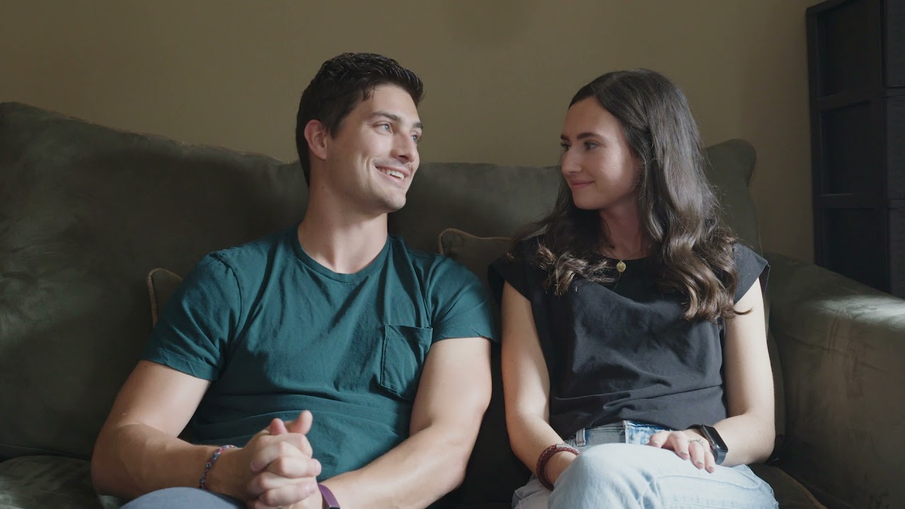 A couple sitting on a gray couch