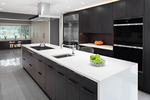 A modern kitchen with dark cabinets and white countertops