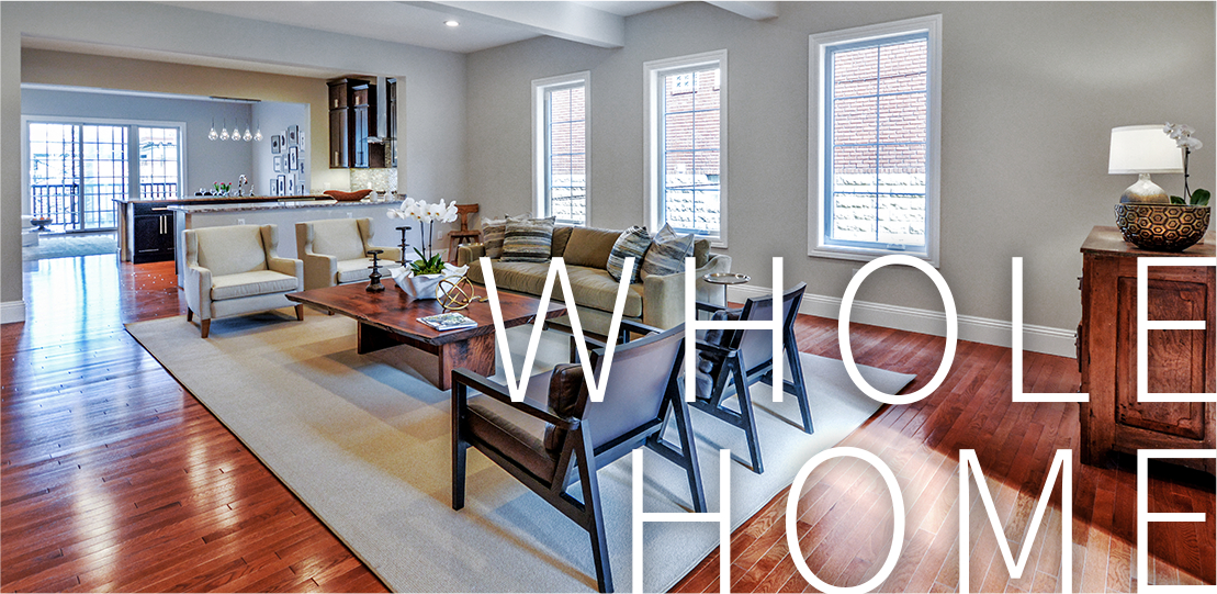 Remodeled living room and kitchen area in a home, with the words "WHOLE HOME" in white over the bottom right corner.