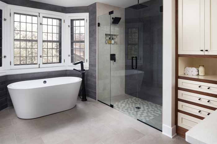 A remodeled bathroom with a standalone tub, a walk in shower, and gray floor and wall tiles