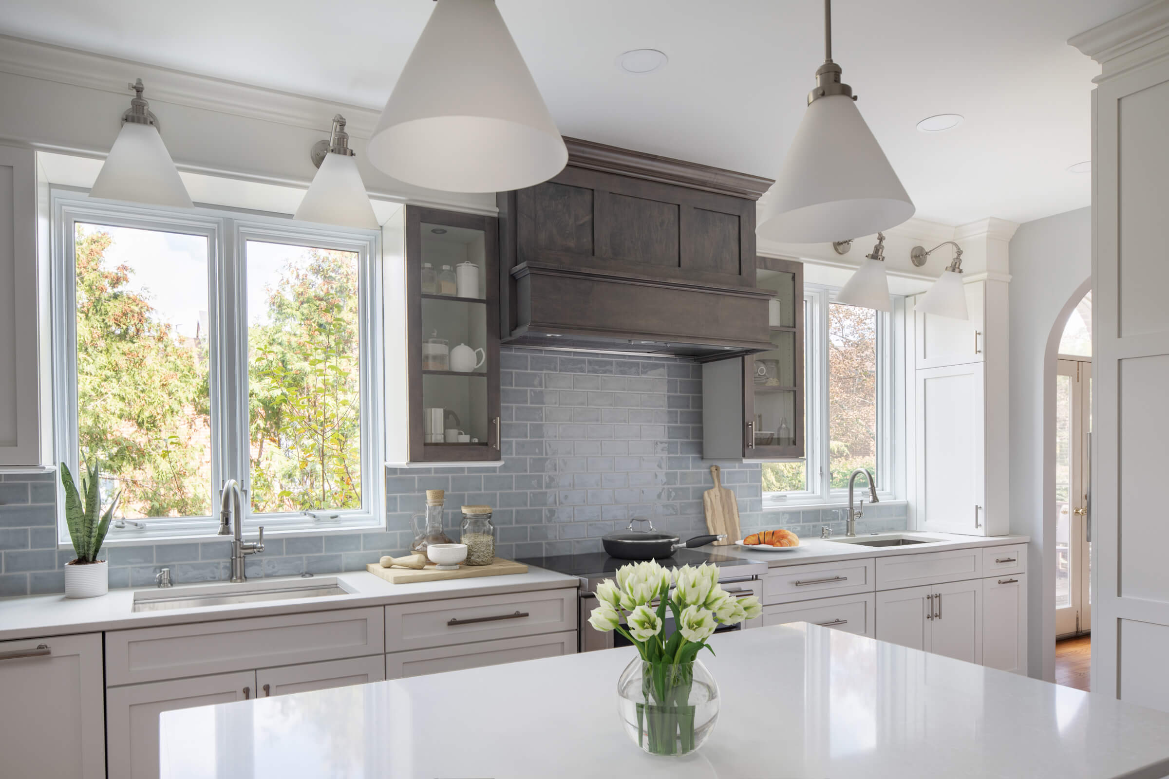 Custom kitchen remodel with white cabinets, white stone countertops, gray subway tile backsplash, and pendant lighting. Kitchen Island