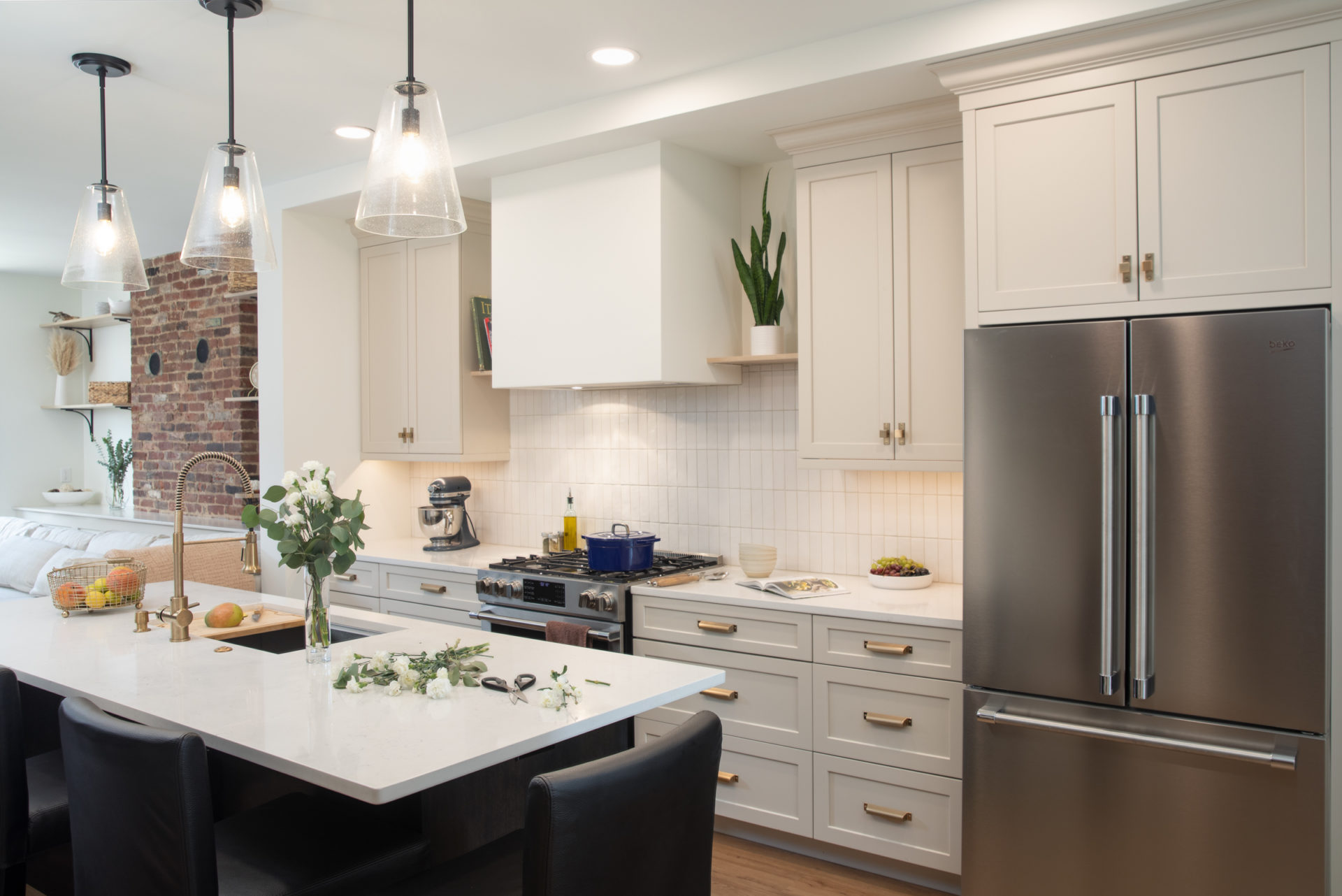 Remodeled kitchen with white cabinets, black island, white quartz countertops, white tile backsplash.
