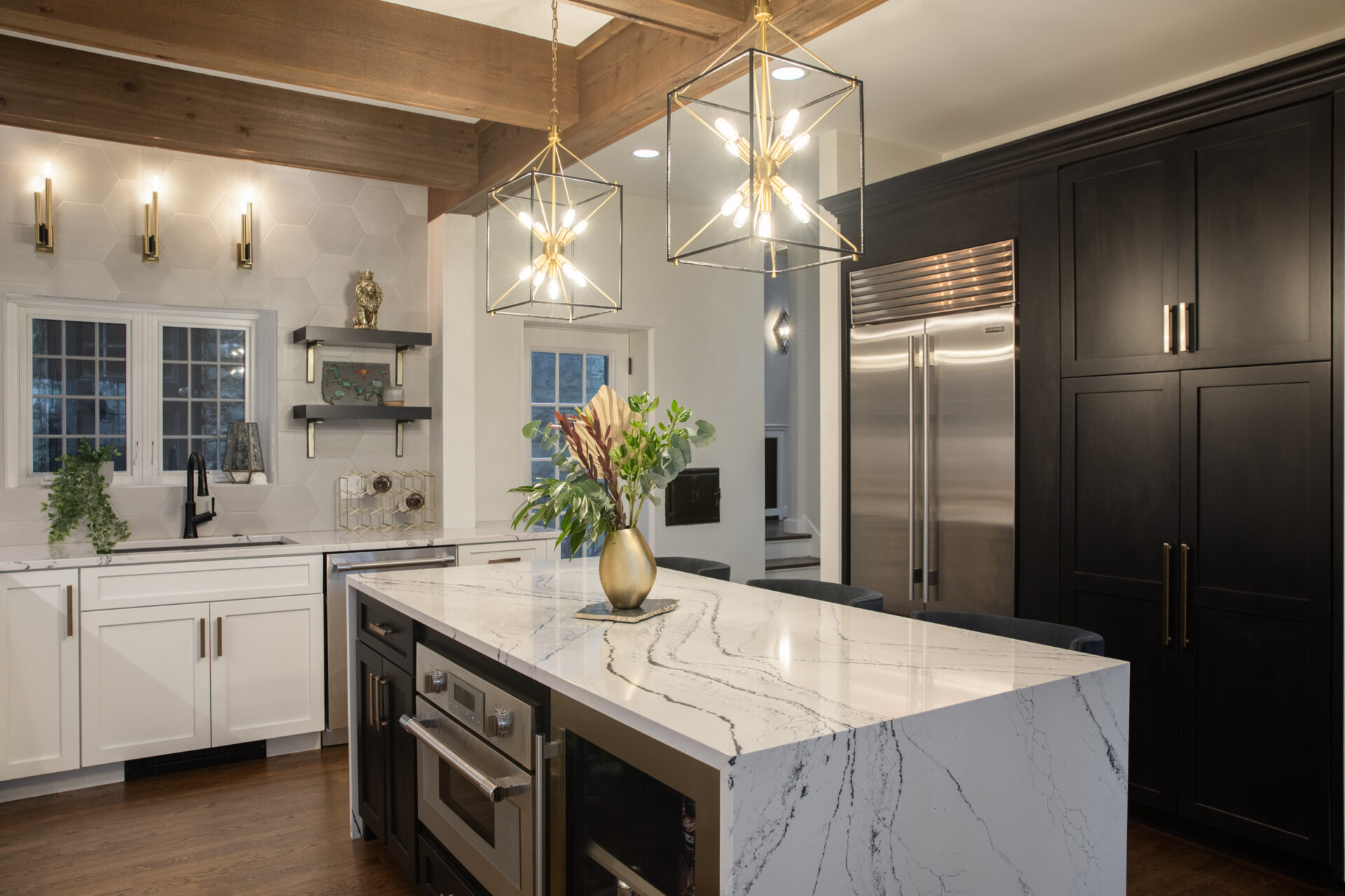 Modern kitchen remodel with white marble waterfall-style countertop, island, white cabinets, and modern pendant lighting over island.